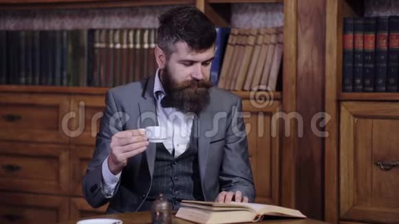 一个可敬的人在图书馆里喝早茶看书一个留着胡子的聪明人看书视频的预览图