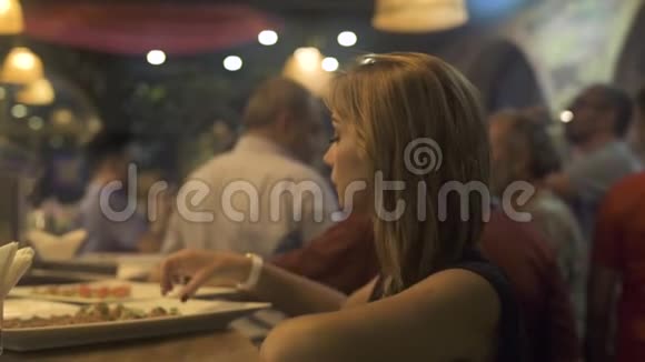 年轻女子在活动桌上吃食物零食在聚会上密切注意女人吃开胃小吃视频的预览图