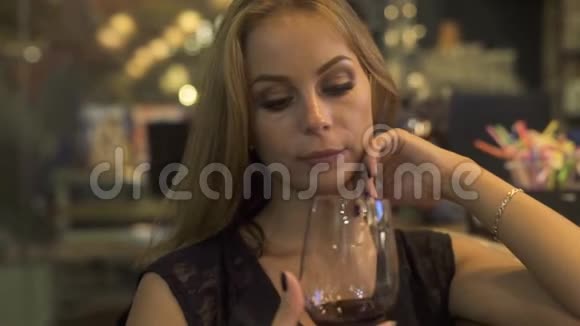 一位年轻女子手拿红酒杯在餐厅里闻到香味品酒的女人视频的预览图