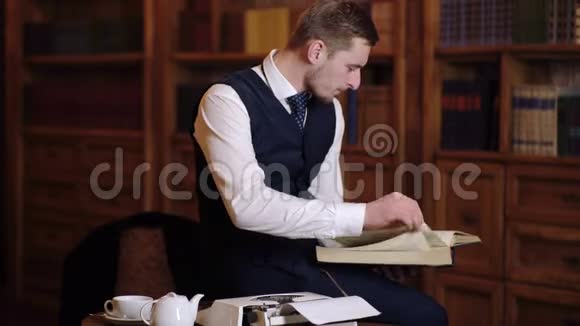一个人坐在图书馆的桌子上看书穿西装的教授在视频的预览图
