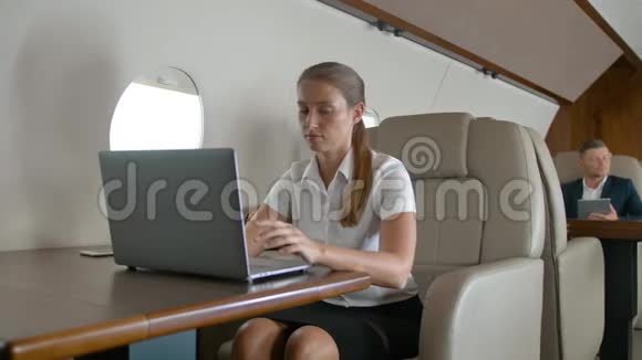 女商人在飞机上使用笔记本电脑视频的预览图