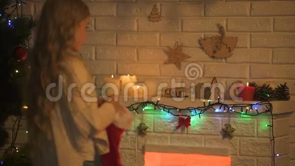 长头发的金发女孩在壁炉上挂着袜子等待圣诞奇迹视频的预览图