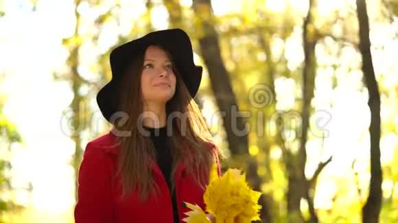 戴着黑帽子的漂亮女孩在秋天的森林里散步天气很好慢动作视频的预览图