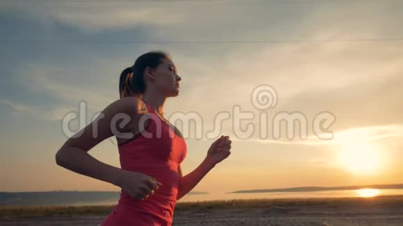 迷人的女士正在日落时沿着海岸线慢跑视频的预览图