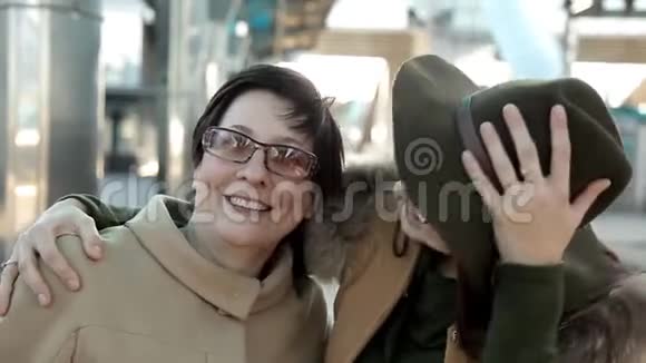 妈妈和成年女儿戴着眼镜在火车站看着镜头微笑着看着视频画像视频的预览图
