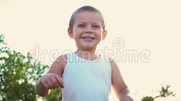 穿着白色t恤的4岁男孩笑着伸出双手活泼开朗的孩子对大自然的描绘视频的预览图
