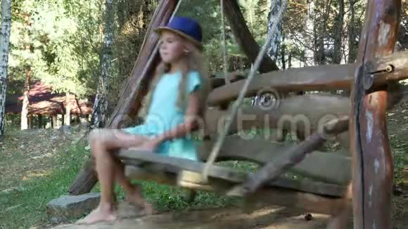 一个温柔美丽的女孩赤脚在秋千上摇摆对着镜头微笑侧面和正面视频的预览图