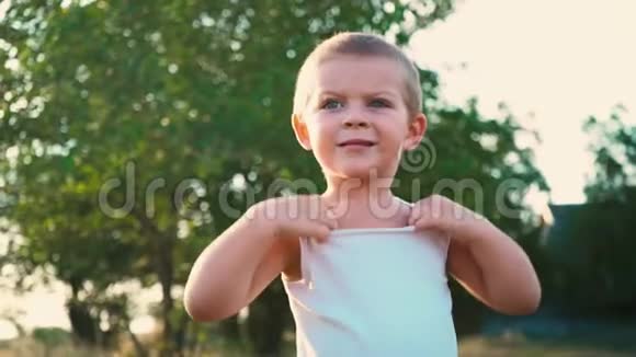 一个活泼开朗的孩子的肖像害羞的孩子把脸的一部分藏在白色T恤下面视频的预览图