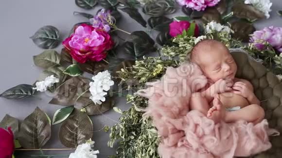 刚出生的男孩带着鲜花睡在摄影区一会儿又闭上眼睛视频的预览图