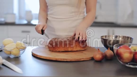 女人切面包的特写镜头在厨房做饭穿着红色指甲的白衬衫的白人女孩现代光视频的预览图