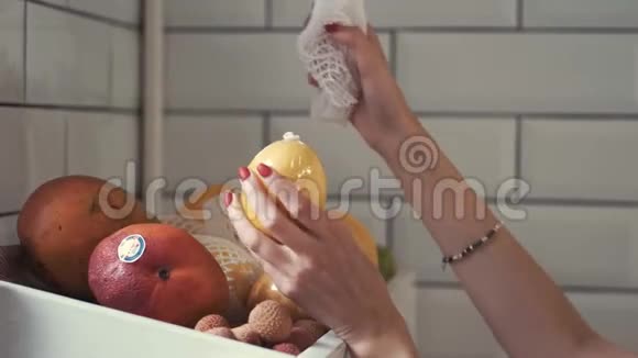 美丽的女人从果架上摘果子做水果篮视频的预览图