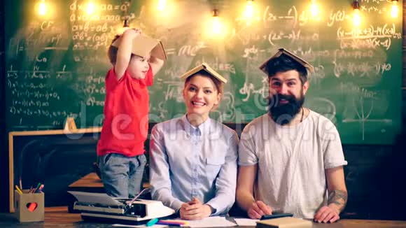 两个大人和一个头上戴着书的男孩在学校里上课很有趣学习观念课堂教师视频的预览图