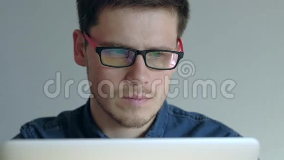 戴眼镜的人在白色背景的笔记本电脑上工作视频的预览图