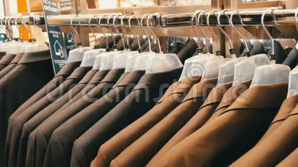 棕色和灰色的男士夹克挂在商场的男士服装店的衣架上一大群男人穿西装视频的预览图