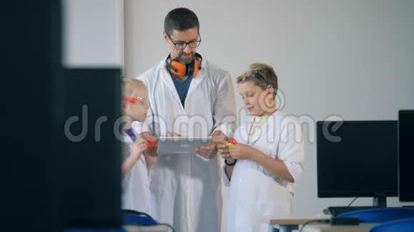 孩子们和一位导师站在实验室的房间里看着新印刷的塑料模型视频的预览图