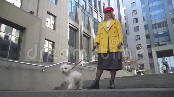 带着狗的年轻女子站在大楼的前面视频的预览图