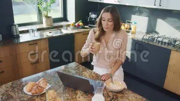 女商人在厨房用电脑说话快乐的女人喝咖啡视频的预览图