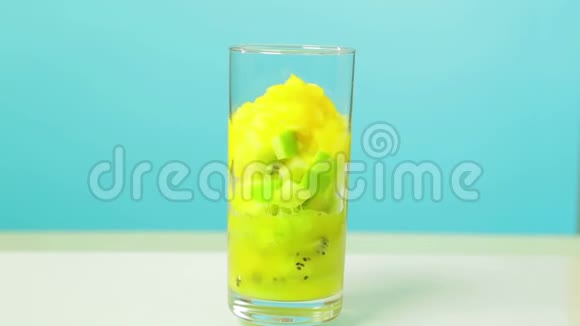 在一杯奇异果和一个苹果切片橙汁倒玻璃旋转成圆视频的预览图