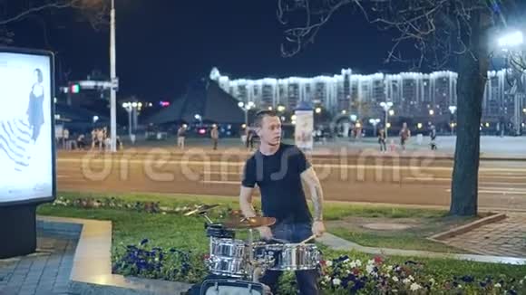 酷街音乐家鼓手在大城市的人行道上演奏晚上街上的酷演视频的预览图