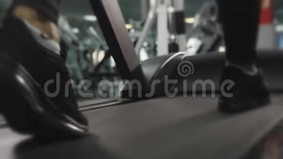 男人在健身房训练他在跑步机上跑步双脚特写健身和有氧运动的概念视频的预览图