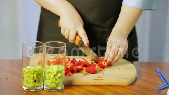 一个女人用一把大刀在木板上切熟的草莓视频的预览图
