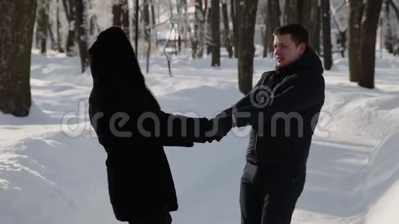 美丽的年轻夫妇牵着手旋转城市冬季公园视频的预览图