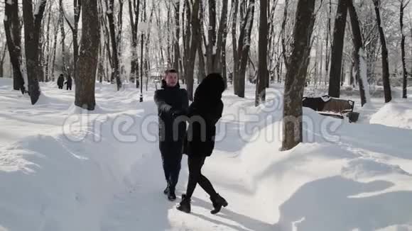 美丽的年轻夫妇牵着手旋转城市冬季公园视频的预览图