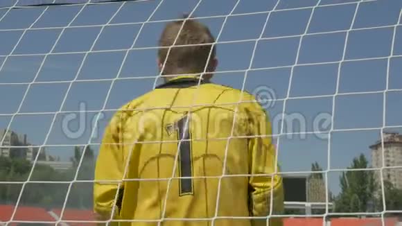 足球比赛中一名身穿黄色制服的足球守门员站在门口背上有一个数字视频的预览图