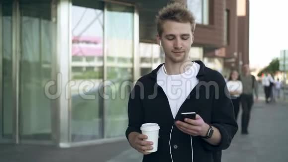 带着智能手机和咖啡听音乐微笑的年轻人视频的预览图