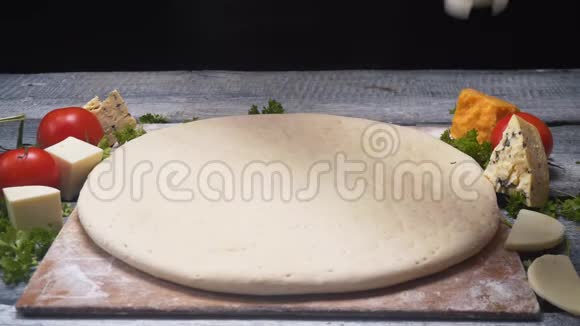 厨师的双手用白色酱汁覆盖在不同配料的木板上的披萨面团框架视频的预览图