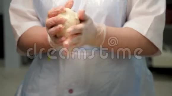 特写镜头一位妇女在面包店用手拿着一块生面团戴着烹饪手套库存录像女性视频的预览图