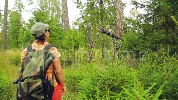 背着背包的年轻女游客穿过森林里的灌木丛中间计划视频的预览图