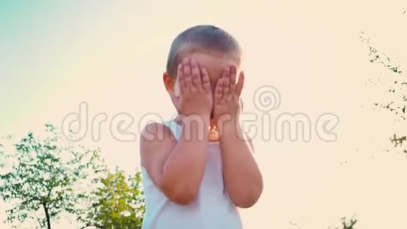 四岁的男孩穿着一件白色的t恤笑着用手捂住脸孩子跳到天空上一幅肖像画视频的预览图