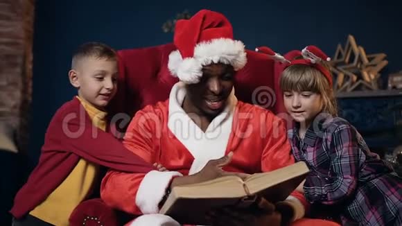 圣诞老人和两个孩子戴着红帽子看书的肖像视频的预览图