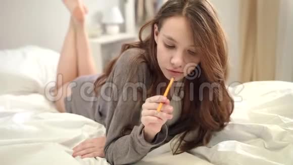 女设计师在卧室画素描躺在床上的年轻女子视频的预览图