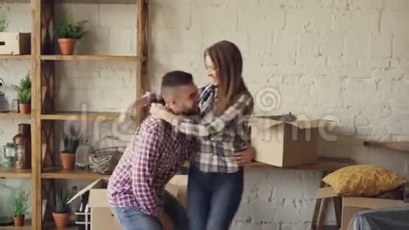 快乐强壮的男人在购买新房子后在搬迁到新房子时旋转他的妻子并亲吻她浪漫浪漫视频的预览图