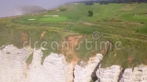 白色悬崖峭壁上的绿色山峰上的步行游客的俯视图行动带线条的海岸悬崖景观视频的预览图