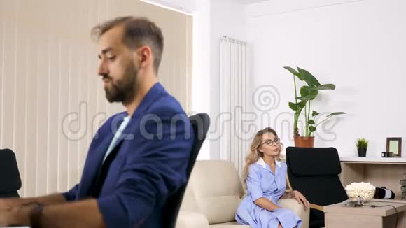 女人看电视吃爆米花而她的男朋友正在电脑上工作视频的预览图