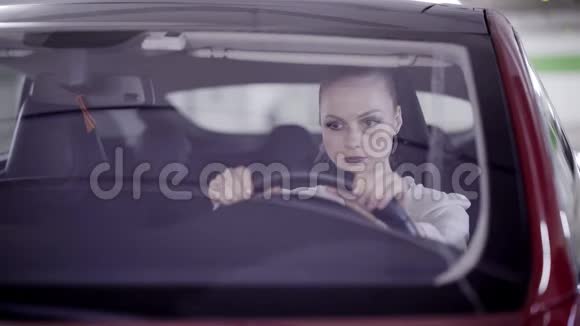 扎着马尾辫的年轻女子坐在红色的车里闭上眼睛盯着方向盘视频的预览图