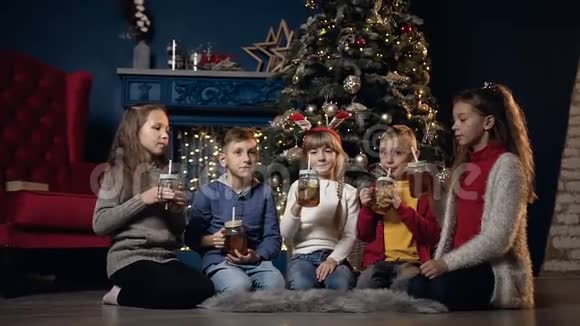 可爱的五个孩子在舒适的房间里的圣诞树背景上喝杯茶视频的预览图