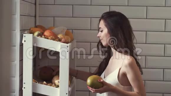 美丽的女人从果架上摘果子做水果篮视频的预览图