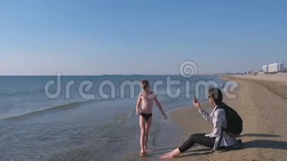 妈妈用手机拍下了儿子在海边散步的小博主的照片和视频视频的预览图
