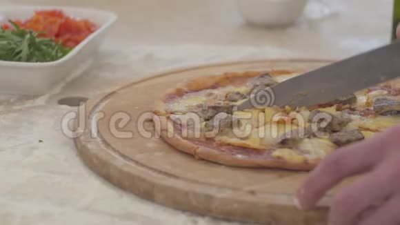 用刀子手工切割盘子木板上的披萨视频的预览图