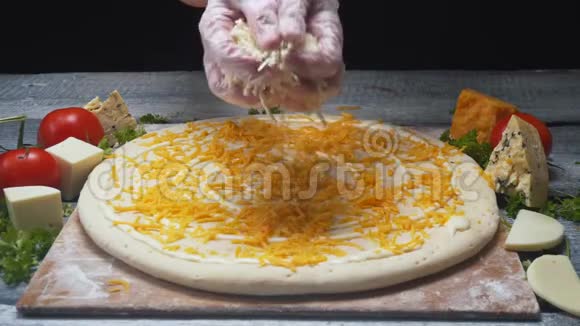 厨师在其他配料前用切达干酪在木板上覆盖比萨饼面团框架视频的预览图