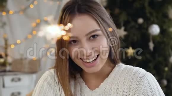 一位年轻的白种人微笑的女士正在用孟加拉火在奢华的圣诞装饰中庆祝新年视频的预览图