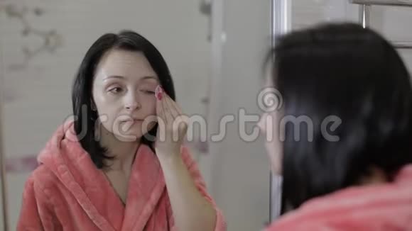 漂亮的黑发女人用棉花垫女人卸妆视频的预览图