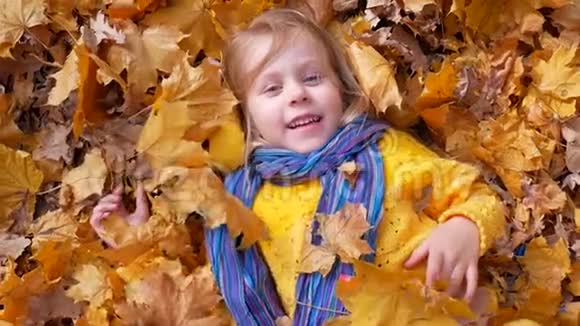 微笑快乐的小女孩躺在秋叶上视频的预览图