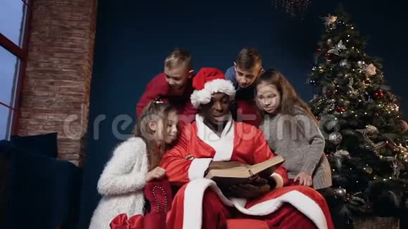 可爱的圣诞老人戴着有趣的帽子看书和孩子视频的预览图