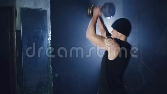 对着镜子的人举起哑铃带蓝色背光的深色健身房视频的预览图