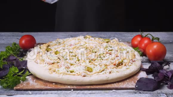 厨师用硅胶手套将香料加入木桌上的比萨饼上框架美味的披萨视频的预览图